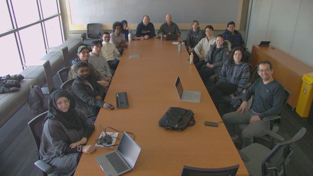 The group seated around a long boardroom table during a group meeting