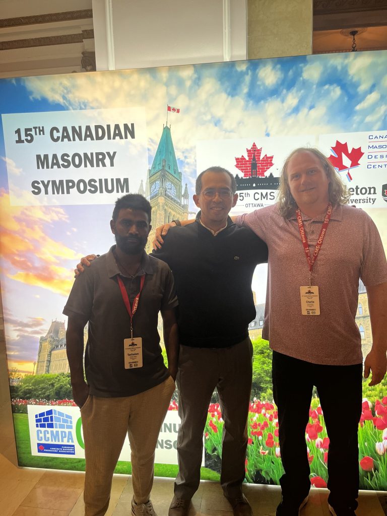 Three group members in front of the 15th Canadian Masonry Symposium backdrop