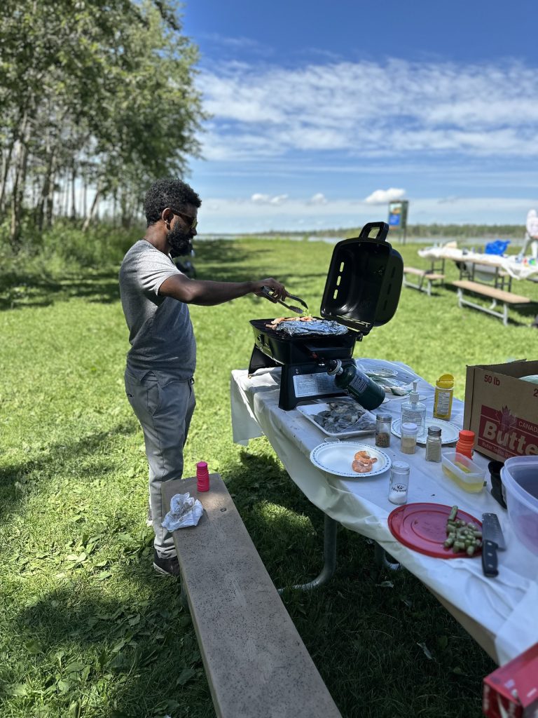 A group member grilling at a picnic table during the 2025 summer BBQ