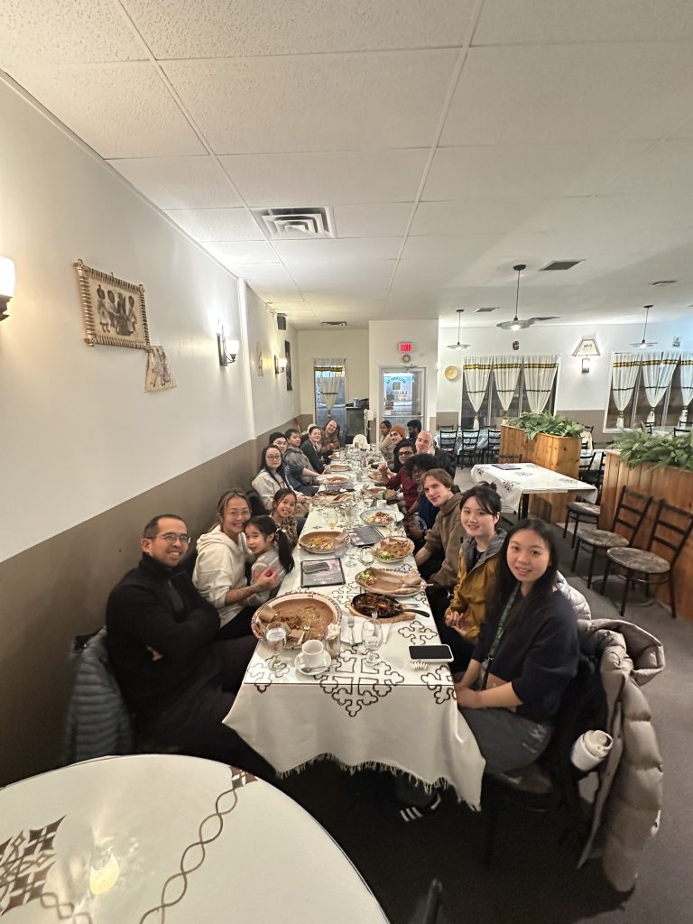 Group members seated along a long dinner table in a restaurant