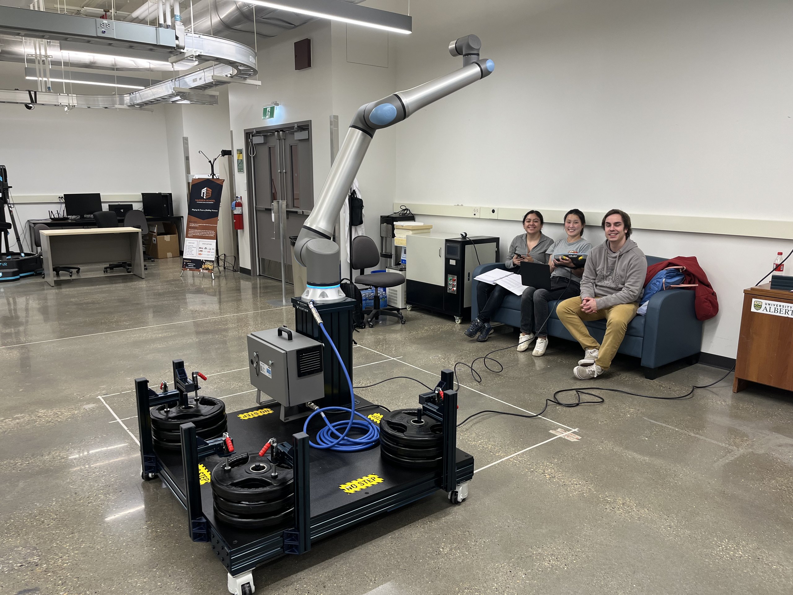 A UR20 robot arm on a mobile Vention pedestal in the IDOBE lab, part of the construction automation research.